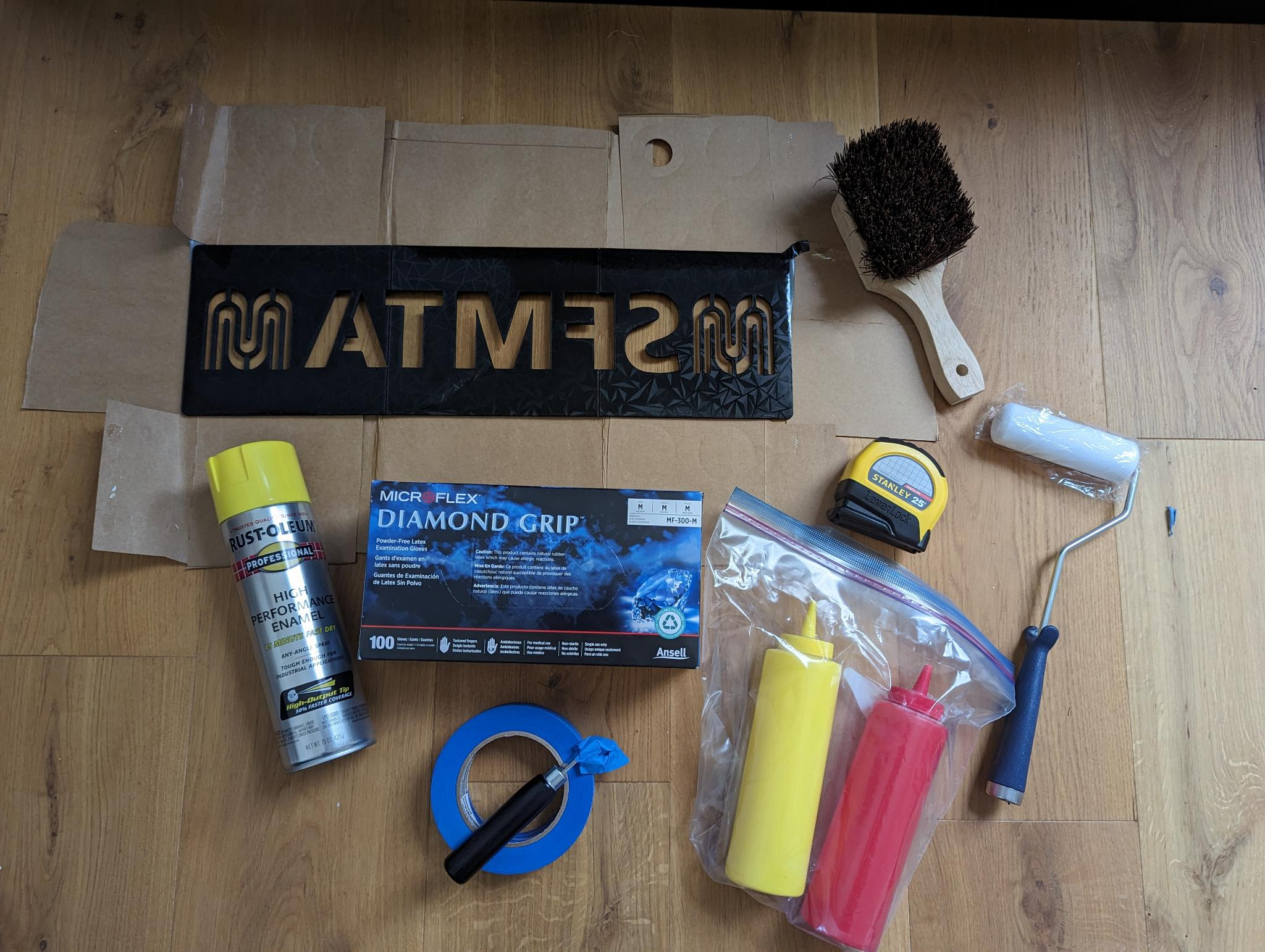 A curb-painting kit with the SFMTA stencil, brush, spraypaint, latex gloves, painters tape, a gardening pick, tape measure, paint roller, and two squeeze bottles in a plastic bag.